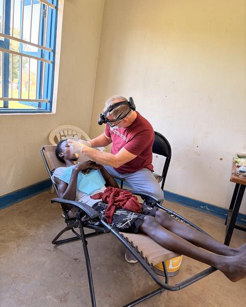 A dentist treating a young patient in a reclining chair