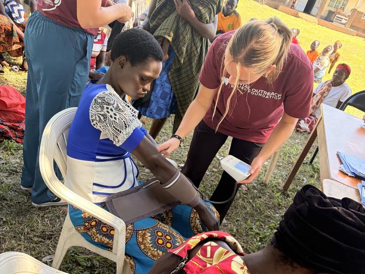 A visiting volunteer examining a woman at an outdoor community outreach